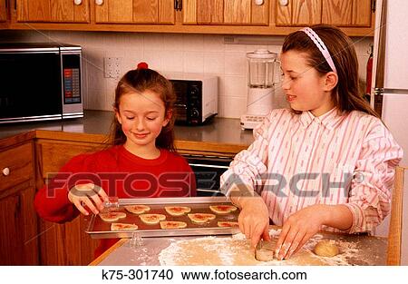 Stock Image - two sisters making cookies. Fotosearch