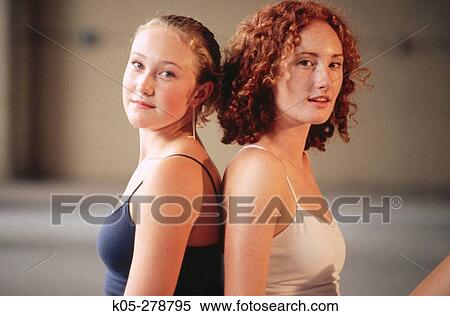 Two sisters wearing tank tops stading back to back View Large Photo Image Stock Photography - Two sisters wearing tank tops stading back to back. Fotosearch