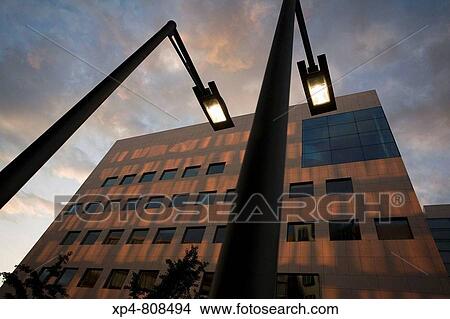 Two streetlights light up at dusk on a city street as shadows play on buildings in the background. Massachusetts, USA View Large Photo Image Picture - Two streetlights light up at dusk on a city street as shadows play on buildings in the background. Massachusetts, USA. Fotosearch