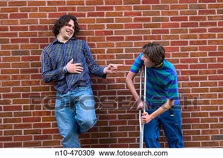 Two teen boys, one on a crutch, standing against a brick wall View Large Photo Image Stock Photo - Two teen boys, one on a crutch, standing against a brick wall. Fotosearch