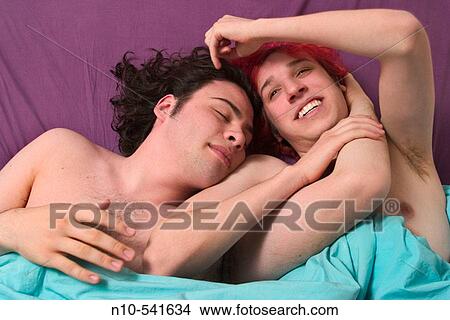Picture - Two teen boys, one with dyed red hair, lying together in bed.. Fotosearch
