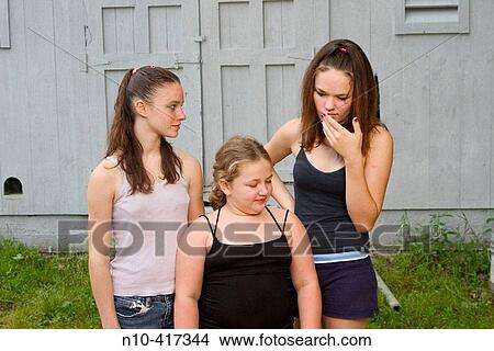 Picture - Two teen girls and their young sister standing together in front of an old barn.. Fotosearch