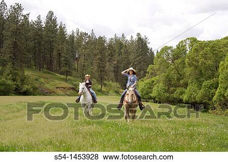Stock Photo - Two teen girls riding horses in Reardan, Washington, USA.. Fotosearch