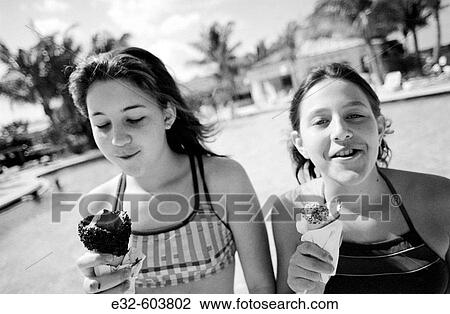 Two teenage girls enjoying eating ice cream together on hot day at the swimming pool View Large Photo Image Stock Image - Two teenage girls enjoying eating ice cream together on hot day at the swimming pool. Fotosearch