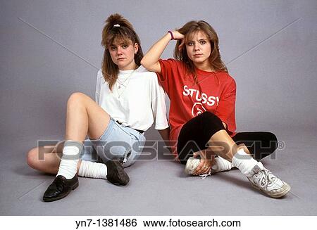 Stock Photograph - two teenage girls sitting on the floor of the studio posing for the camera but not showing a lot of enthusiasm. Fotosearch