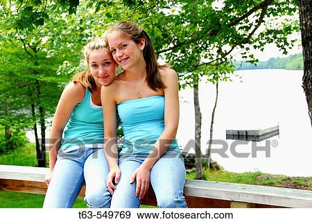 two teenage girls sitting together on railing at the cottage View Large Photo Image Stock Photo - two teenage girls sitting together on railing at the cottage. Fotosearch