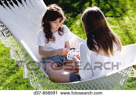 Two teenagers playing cards in the garden View Large Photo Image Stock Image - Two teenagers playing cards in the garden. Fotosearch