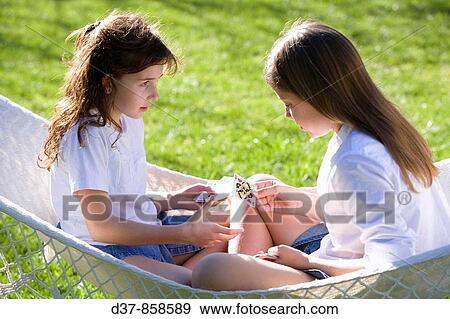 Two teenagers playing cards in the garden View Large Photo Image Stock Photo - Two teenagers playing cards in the garden. Fotosearch