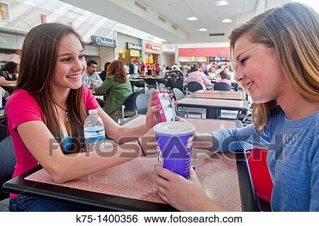 Stock Photograph - Two teens enjoying a break from shopping with a beverage. Fotosearch