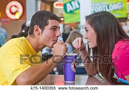 Stock Photography - Two teens sharing a beverage and a smile. Fotosearch