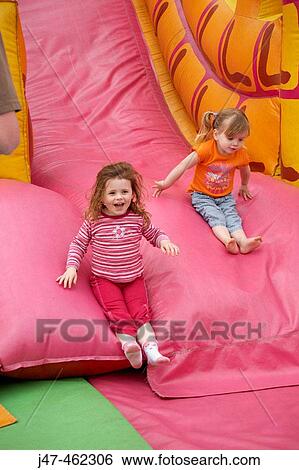 Two three year old girls sliding down a big bouncy slide. View Large Photo Image Stock Photograph - Two three year old girls sliding down a big bouncy slide.. Fotosearch