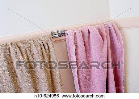 Two towels, one brown and one pink, hanging on a bathroom towel rack. View Large Photo Image Stock Photograph - Two towels, one brown and one pink, hanging on a bathroom towel rack.. Fotosearch