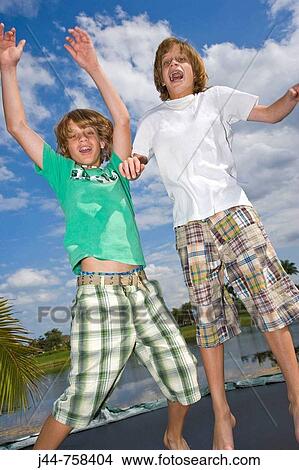 Two twin brothers jumping on trampoline outdoors View Large Photo Image Picture - Two twin brothers jumping on trampoline outdoors. Fotosearch