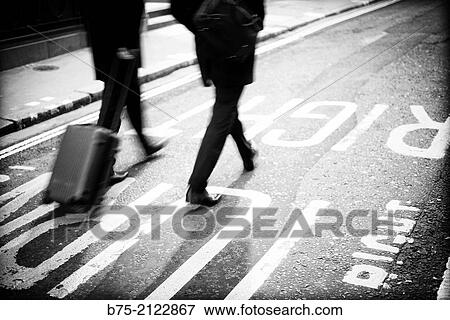 two unrecognizable and relaxed on executive walking down the middle of the street pulling a suitcase in London, England, UK, Europe View Large Photo Image Stock Photo - two unrecognizable and relaxed on executive walking down the middle of the street pulling a suitcase in London, England, UK, Europe. Fotosearch