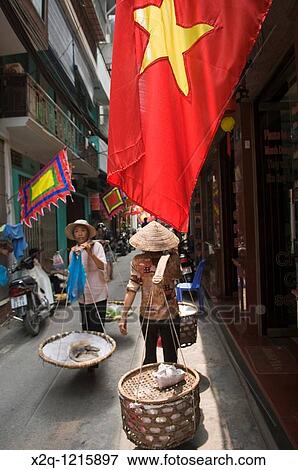 Two Vietnamese women carrying panniers in an alley in the old quarter of Hanoi Vietnam View Large Photo Image Stock Photo - Two Vietnamese women carrying panniers in an alley in the old quarter of Hanoi Vietnam. Fotosearch