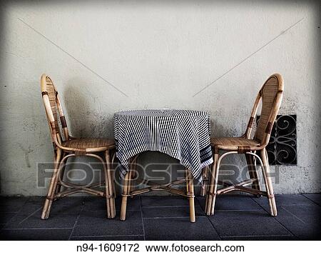 Two wicker chairs with a table and tablecloth on the terrace of a bar. View Large Photo Image Stock Image - Two wicker chairs with a table and tablecloth on the terrace of a bar.. Fotosearch
