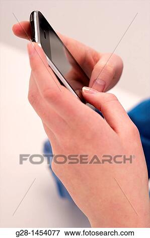 Two woman's hands holding a phone and typing sending an e-mail View Large Photo Image Stock Photo - Two woman's hands holding a phone and typing sending an e-mail. Fotosearch