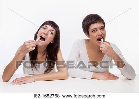 Two women brushing teeth View Large Photo Image Stock Photo - Two women brushing teeth. Fotosearch