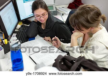 Two women checking paperwork in their cubicle View Large Photo Image Picture - Two women checking paperwork in their cubicle. Fotosearch