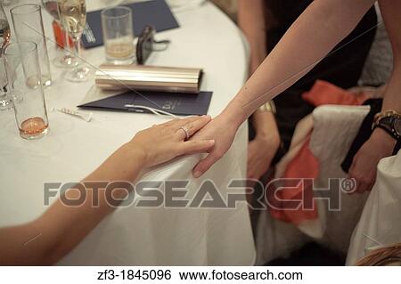Two women holding their hands on a restaurant table View Large Photo Image Stock Photograph - Two women holding their hands on a restaurant table. Fotosearch