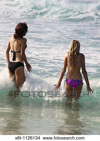 Picture - Two Women In The Ocean - Two young women just entering the ocean on the Big Island of Hawaii, USA. Fotosearch