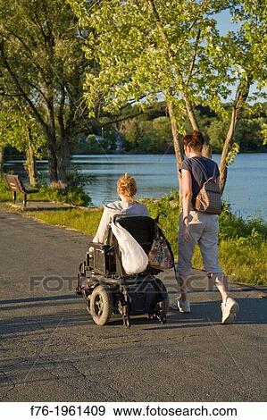 Two women on roadway, one in wheelchair and one walking next to her. View Large Photo Image Stock Photo - Two women on roadway, one in wheelchair and one walking next to her.. Fotosearch