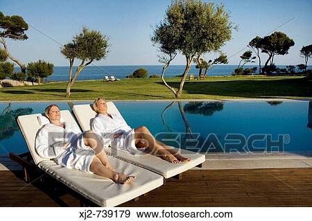 Two women relaxing on a sun lounger in a Hotel by the sea View Large Photo Image Stock Photo - Two women relaxing on a sun lounger in a Hotel by the sea. Fotosearch