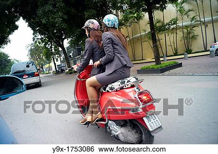 Two women riding on a red scooter on the streets in Vietnam View Large Photo Image Stock Photograph - Two women riding on a red scooter on the streets in Vietnam. Fotosearch