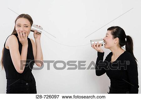 Stock Photo - two women using tin can. Fotosearch