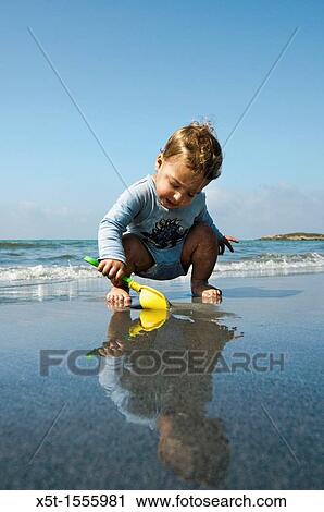Two year baby boy plays on the beach View Large Photo Image Stock Image - Two year baby boy plays on the beach. Fotosearch