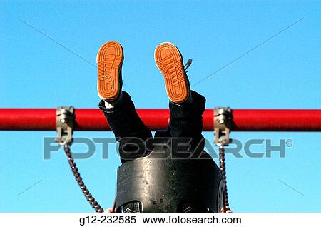 Stock Photography - Two-year old boy on swing with feet in the air. Fotosearch