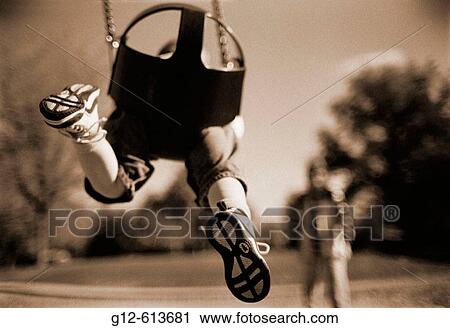 Two-year old boy on swing with woman in background View Large Photo Image Stock Image - Two-year old boy on swing with woman in background. Fotosearch