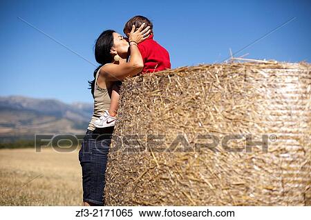 Two year old boy sitting on a straw and kissing a middle age woman View Large Photo Image Stock Photography - Two year old boy sitting on a straw and kissing a middle age woman. Fotosearch