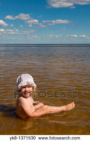 Stock Image - Two Years Old Baby Girl Sitting in Water. Fotosearch