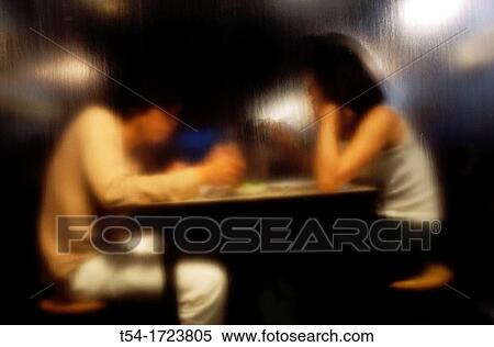 Two young Asians eating, photographed through glass, runs down to the water. View Large Photo Image Stock Photography - Two young Asians eating, photographed through glass, runs down to the water.. Fotosearch