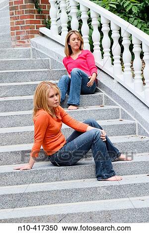 Two young blond women, who are sisters, sitting on different steps of a staircase. View Large Photo Image Stock Image - Two young blond women, who are sisters, sitting on different steps of a staircase.. Fotosearch
