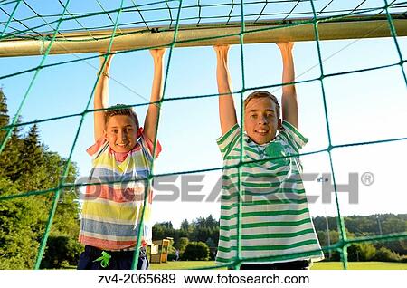 Two young boys doing chin-ups on a goal, Germany. View Large Photo Image Stock Photo - Two young boys doing chin-ups on a goal, Germany.. Fotosearch