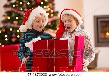 Two young boys opening a Christmas present on Christmas day View Large Photo Image Stock Image - Two young boys opening a Christmas present on Christmas day. Fotosearch