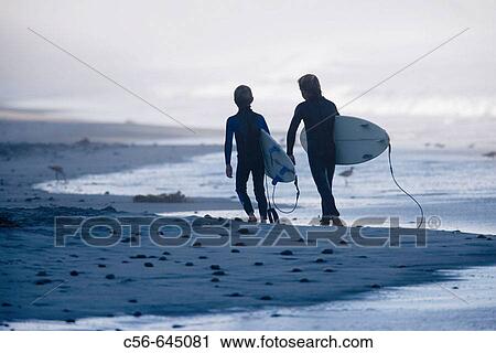 Two young boys walking down and sand and pebblestone beach carrying there. surfboards. View Large Photo Image Stock Image - Two young boys walking down and sand and pebblestone beach carrying there. surfboards.. Fotosearch