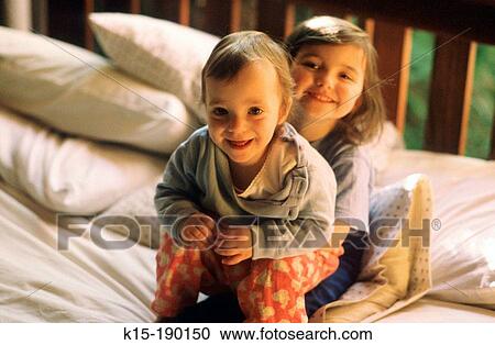 Two young children playing on bed View Large Photo Image Stock Image - Two young children playing on bed. Fotosearch