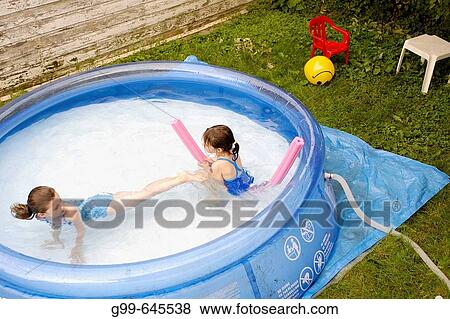 Two young girls, friends actually, playing in the backyard swimming pool in Windsor, Ontario, Canada. View Large Photo Image Stock Photo - Two young girls, friends actually, playing in the backyard swimming pool in Windsor, Ontario, Canada.. Fotosearch