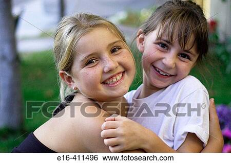 Two young girls hugging View Large Photo Image Stock Photograph - Two young girls hugging. Fotosearch