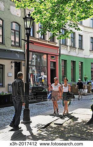Stock Image - two young girls walking in a street of the Old Town of Riga, Latvia, Baltic region, Northern Europe. Fotosearch