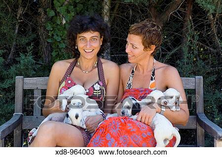 Stock Image - two young girls with a dog puppies of the English Setter breed. Fotosearch
