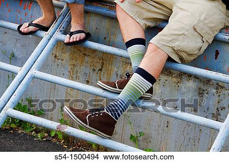 Picture - Two young men, one wearing unusual shoes and socks.. Fotosearch