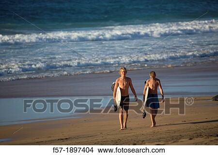 Two young surfers on El Cotillo beach in Fuerteventura, Spain View Large Photo Image Picture - Two young surfers on El Cotillo beach in Fuerteventura, Spain. Fotosearch