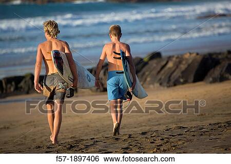 Stock Photograph - Two young surfers on El Cotillo beach in Fuerteventura, Spain. Fotosearch