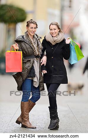 Two young woman with their bags from a shopping tour in a city in Germany. View Large Photo Image Picture - Two young woman with their bags from a shopping tour in a city in Germany.. Fotosearch