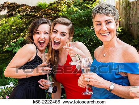 Stock Photograph - two young women and a middle-aged woman at an outdoor celebration.. Fotosearch