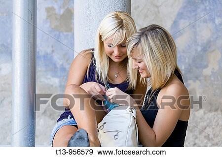 Two young women and a money wallet View Large Photo Image Stock Photo - Two young women and a money wallet. Fotosearch